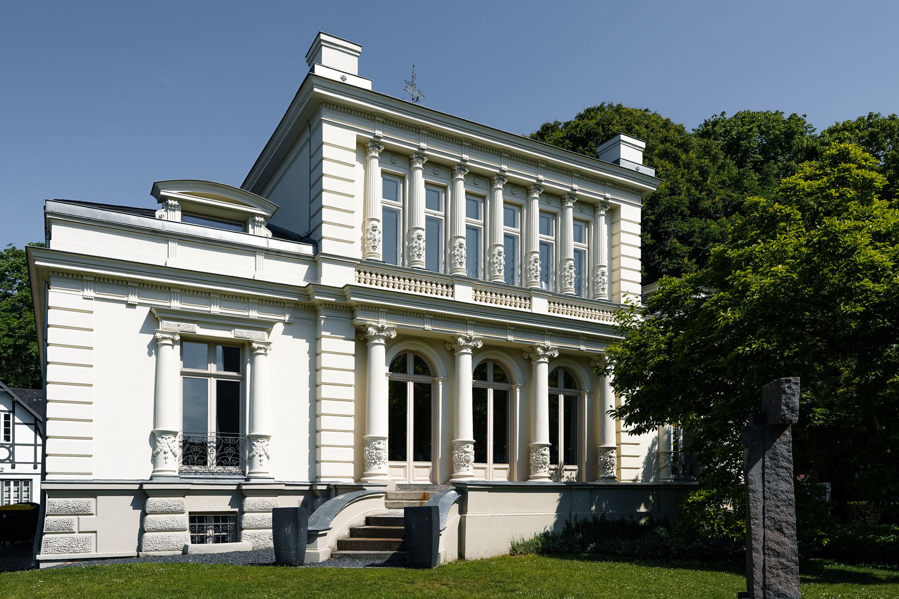 Klassizistische Villa mit weiss lackierten Holzfenstern und Saeulenportal