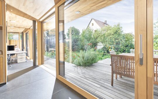 Innenansicht mit eingeschossiger UNILUX FineLine Pfosten-Riegel-Fassade und Hebe-Schiebe-Element aus Holz und Aluminium