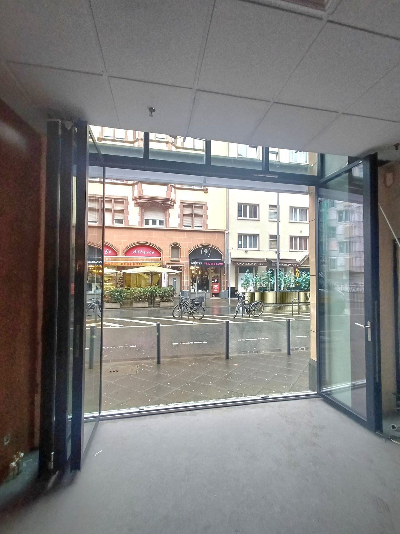 Teilweise geöffnete Glas-Faltanlage mit schwellenlosem Übergang vom Ladenlokal auf den Gehweg