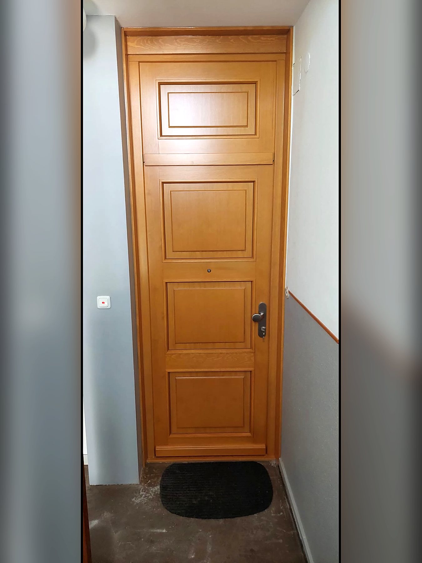Haustür aus hellem Holz mit vier Kassettenfüllungen, gesehen von innen im Treppenhaus
