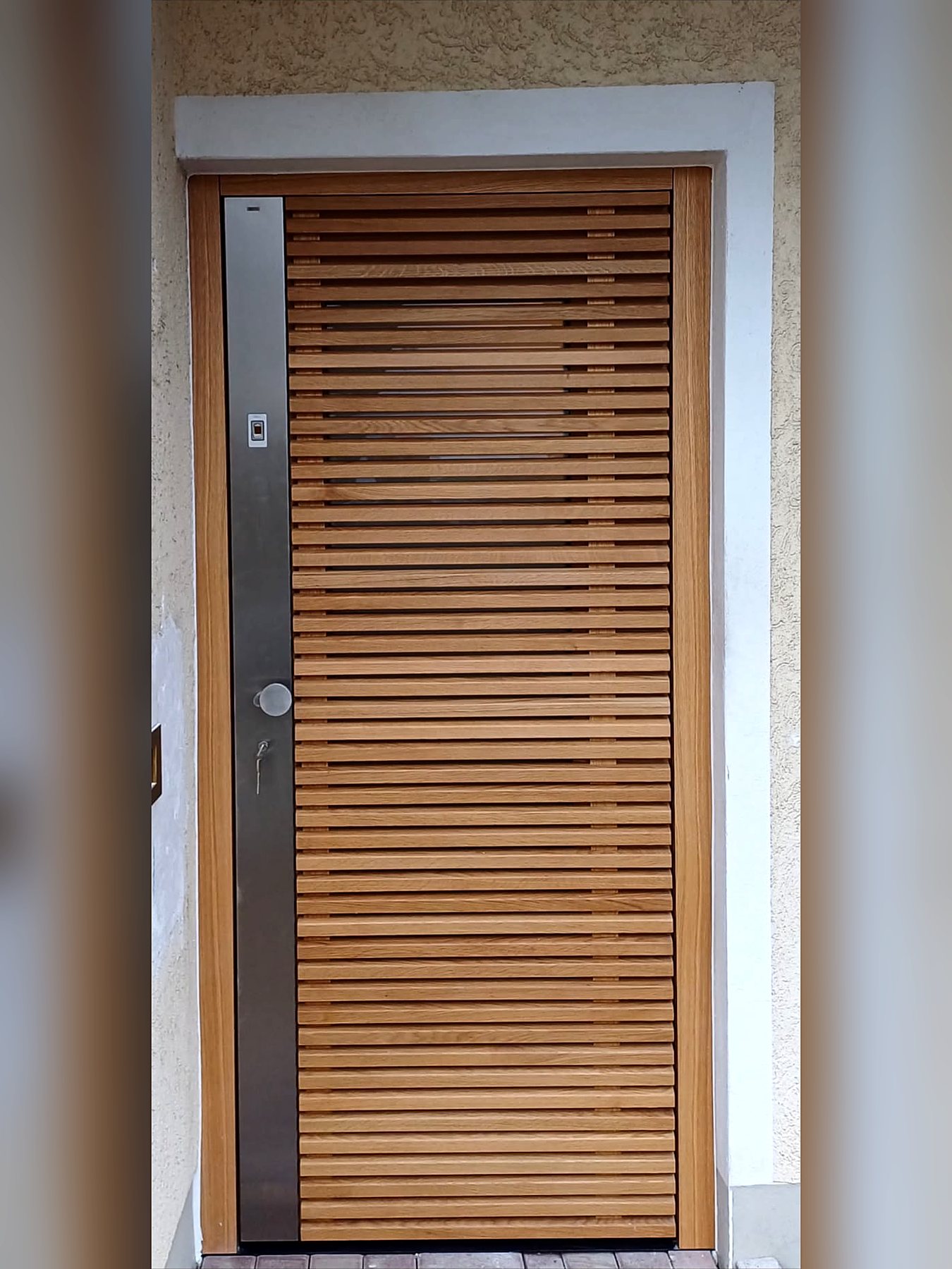 Haustür aus waagerechten Holzlamellen in einem hellen Rahmen
